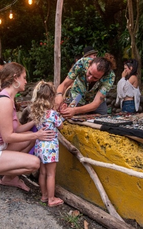 Artists helping a girl put on a bracelet